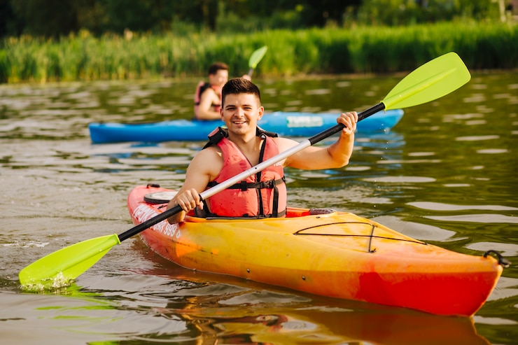 Photo gratuit homme souriant pagayant un kayak sur le lac