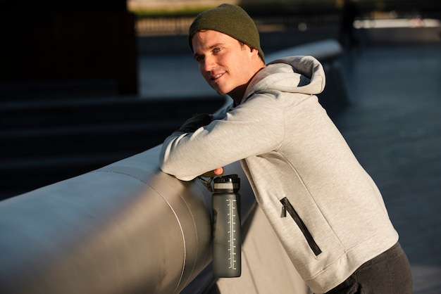 Homme souriant de plan moyen avec une bouteille d'eau