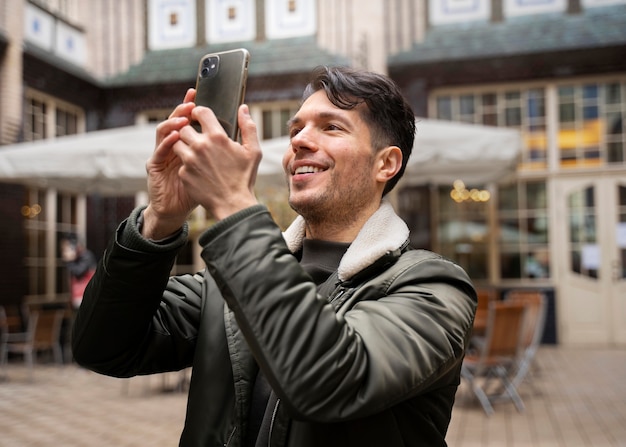 Homme souriant à plan moyen prenant des photos