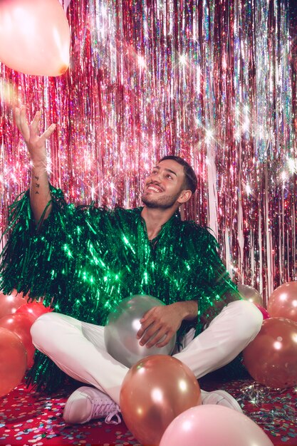 Homme souriant plein coup posant avec des ballons