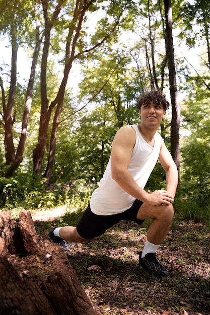 Homme souriant plein coup qui s'étend dans la nature