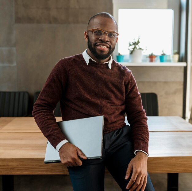 Homme souriant portant un ordinateur portable