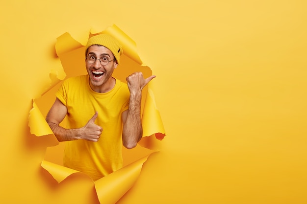 Homme souriant posant à travers du papier déchiré