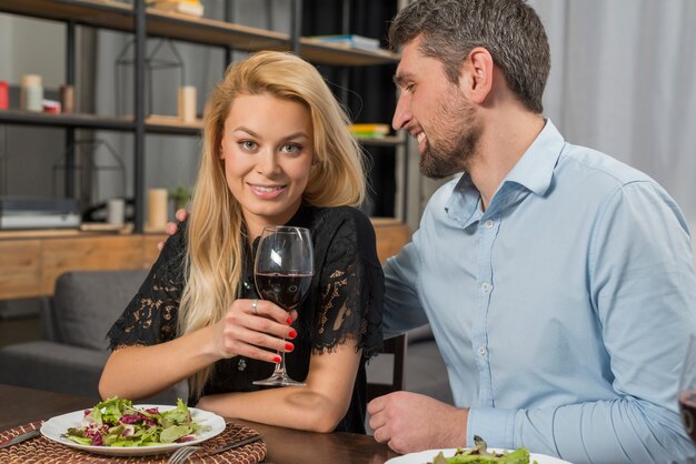 Homme souriant près de femme joyeuse avec verre à table