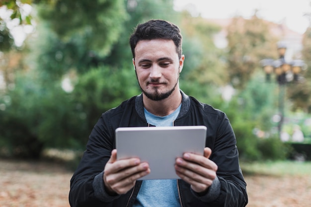 Photo gratuite homme souriant à la recherche dans une tablette