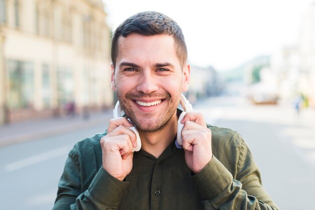 Homme souriant, regardant la caméra tenant un casque autour de son cou