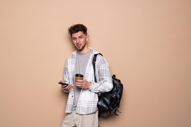 Homme souriant regardant un téléphone portable isolé sur fond beige