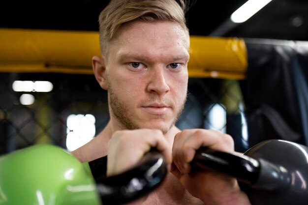 Homme souriant s'entraînant avec des kettlebells