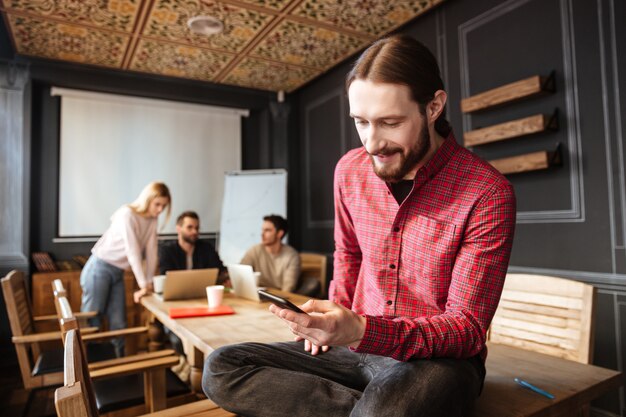 Homme souriant, séance, dans, bureau, regarder téléphone