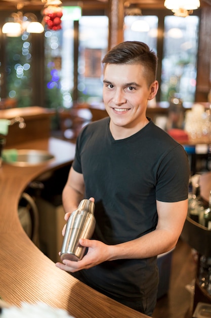 Homme souriant avec un shaker à cocktail
