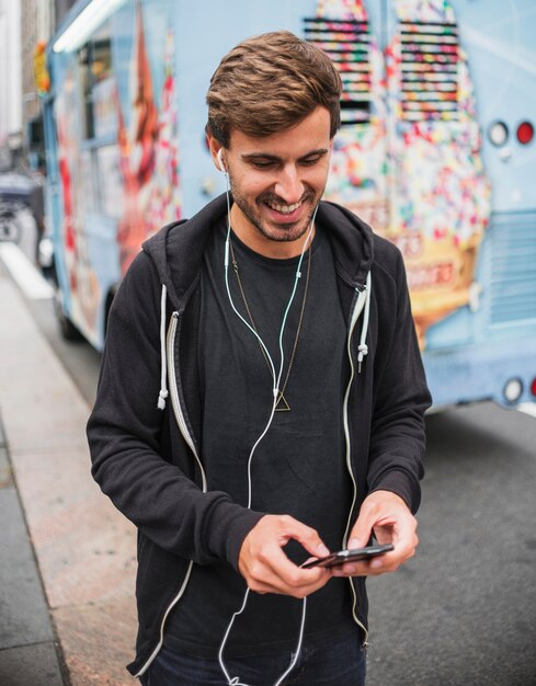 Homme souriant tapant sur un téléphone