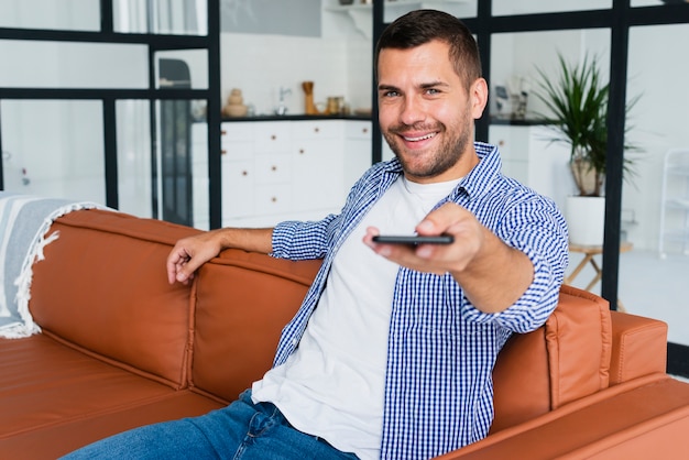Homme souriant avec téléphone à la main sur le canapé