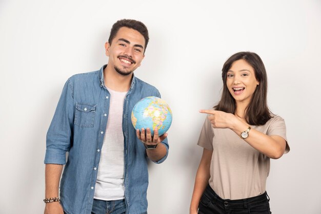 Homme souriant tenant un globe à côté d'une fille positive.