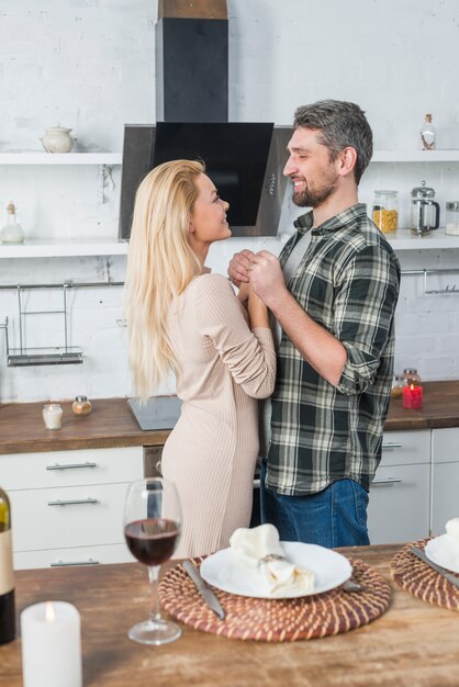 Homme souriant, tenant mains, à, femme joyeuse, près, table, à, verre vin, et, plaque