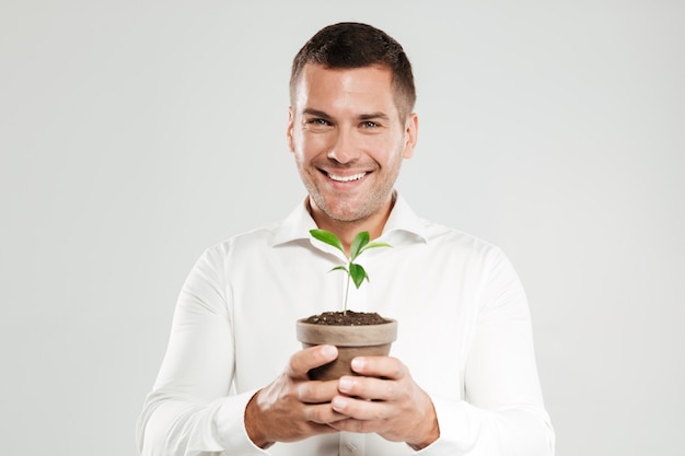 Homme souriant tenant une plante.