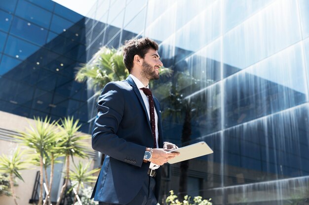 Homme souriant vue de côté avec tablette à l'extérieur