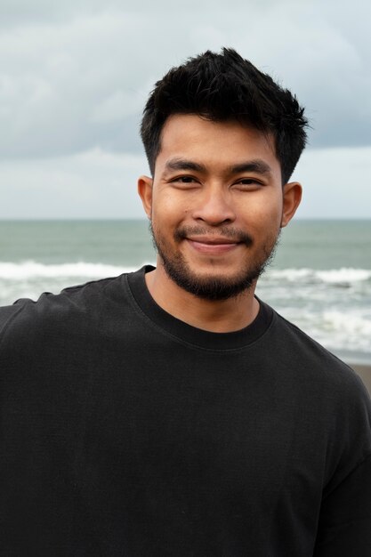 Homme souriant vue de face au bord de la mer