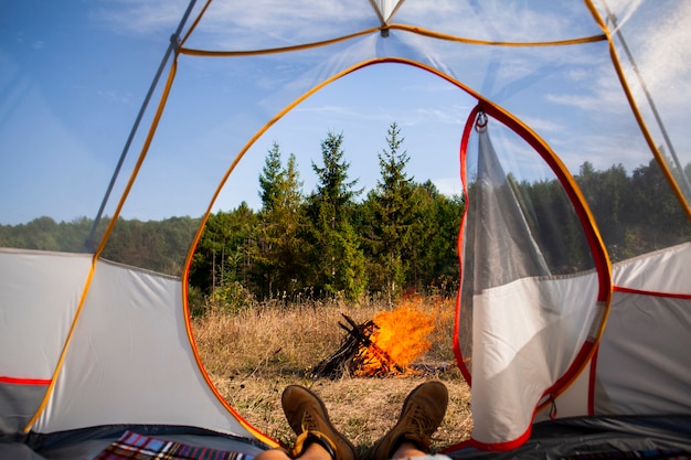 Homme sous la tente en regardant le feu de camp