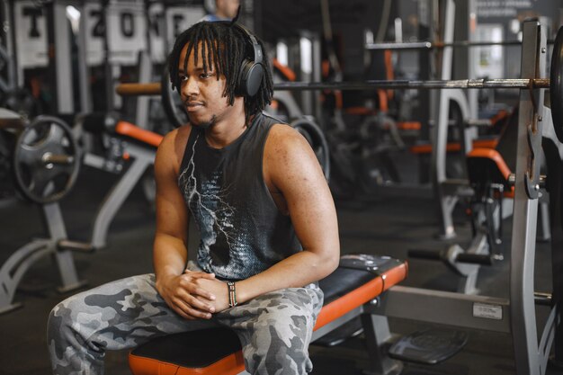 Homme de sport dans la salle de gym. Un homme noir effectue des exercices. Mec en t-shirt noir