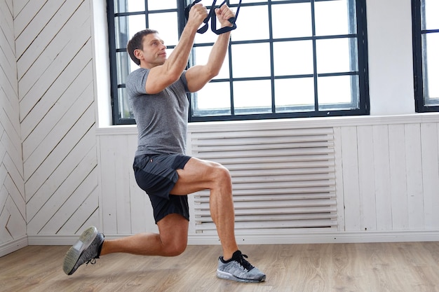 Homme sportif d'âge moyen faisant de l'exercice avec un extenseur dans un club de gym.