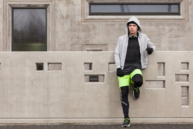 Homme sportif appuyé contre un mur