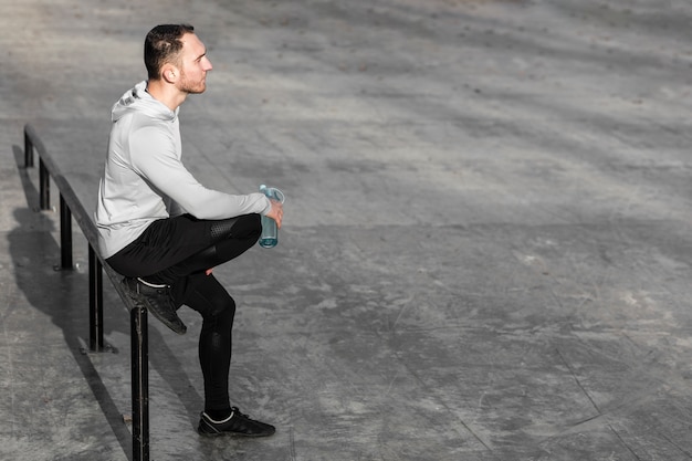 Homme sportif au repos et tenant une bouteille d'eau