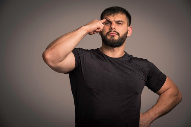 L'homme sportif en chemise noire a l'air pensif.