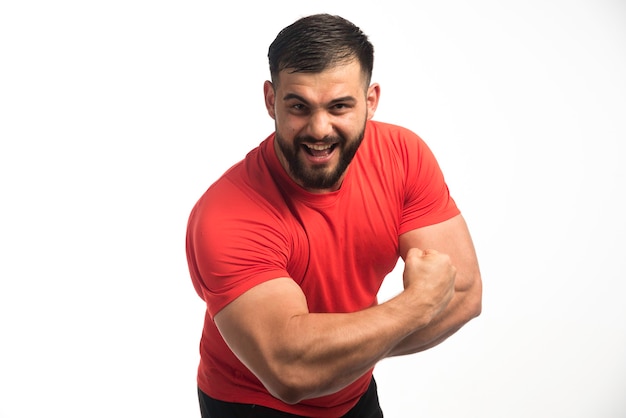 Photo gratuite homme sportif en chemise rouge démontrant ses muscles du bras