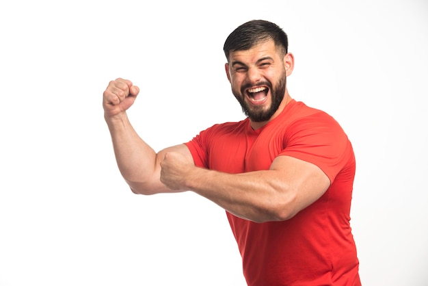 Photo gratuite homme sportif en chemise rouge démontrant ses muscles du bras.