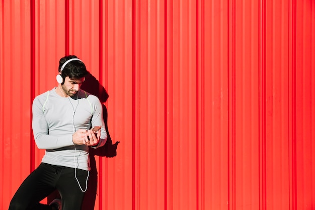 Homme sportif dans les écouteurs en utilisant un smartphone