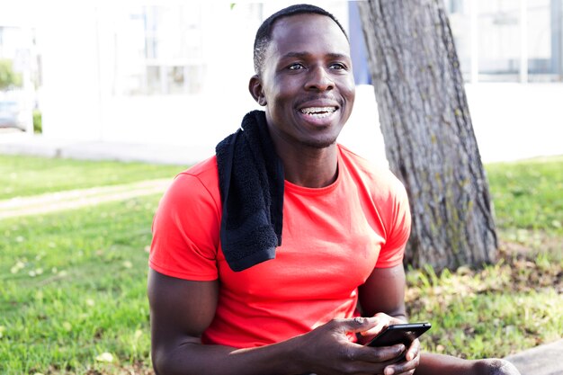 Homme sportif dans le parc en regardant smartphone