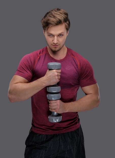 Un homme sportif dans un t-shirt rouge tient des haltères.