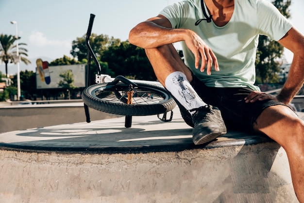 Photo gratuite homme sportif debout près d'un vélo de bmx