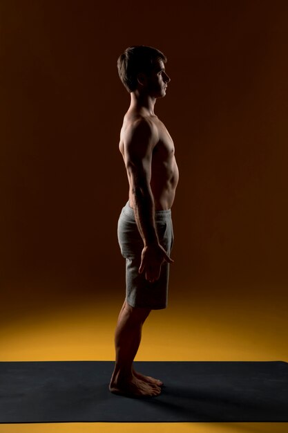 Homme sportif debout sur un tapis de yoga