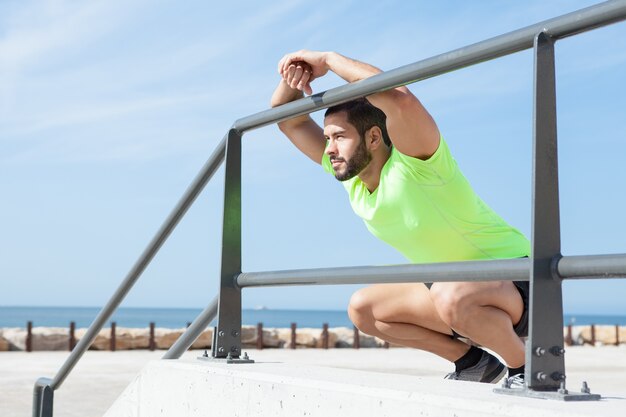 Homme sportif détendu assis et penché sur les barrières