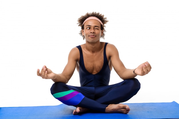 Photo gratuite homme sportif méditant, assis sur un tapis de yoga