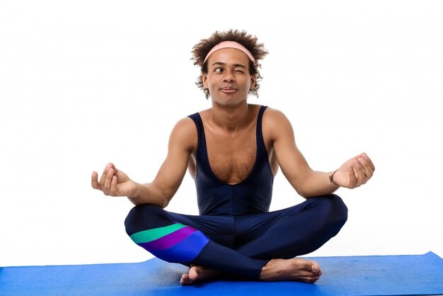 Homme sportif méditant, assis sur un tapis de yoga