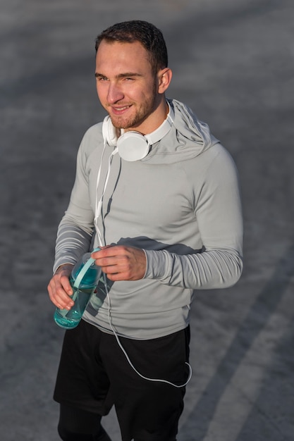 Homme sportif souriant tenant une bouteille d'eau