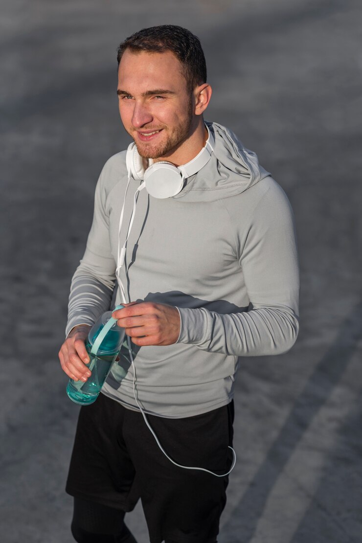 Photo gratuit homme sportif souriant tenant une bouteille d'eau