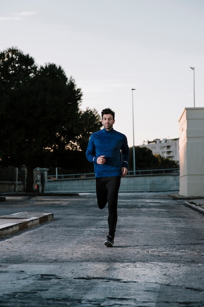 Homme en sportswear jogging sur la rue