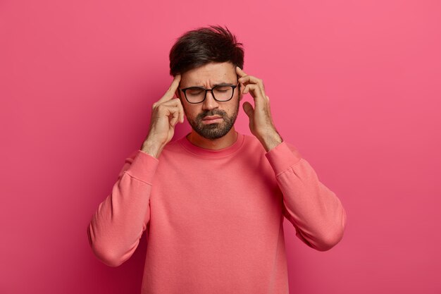 L'homme stressé se frotte les tempes, a mal à la tête, ferme les yeux pour soulager la douleur