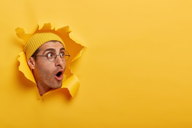 Photo gratuite l'homme stupéfait a l'air avec une grande surprise ou de la peur de côté, ouvre largement la bouche, porte un chapeau et des lunettes rondes