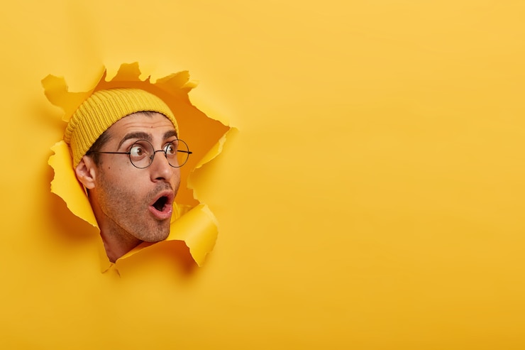 Photo gratuit l'homme stupéfait a l'air avec une grande surprise ou de la peur de côté, ouvre largement la bouche, porte un chapeau et des lunettes rondes