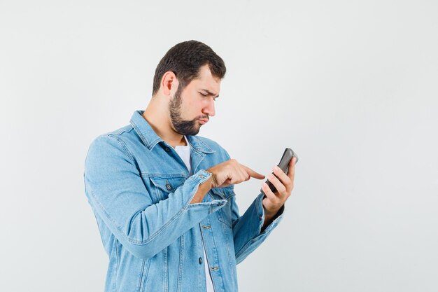 Homme de style rétro appelant quelqu'un en veste, t-shirt et ayant l'air concentré.