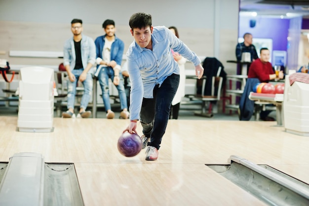 Homme sud-asiatique en chemise jeans debout au bowling et lancer la balle