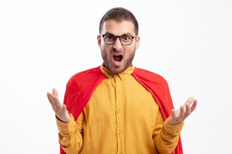 Photo gratuit homme de super-héros en colère dans des lunettes optiques avec manteau rouge se tient la main ouverte isolé sur un mur blanc