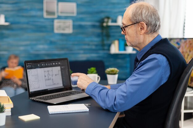 Homme supérieur travaillant avec un ordinateur portable pour faire un plan d'accueil