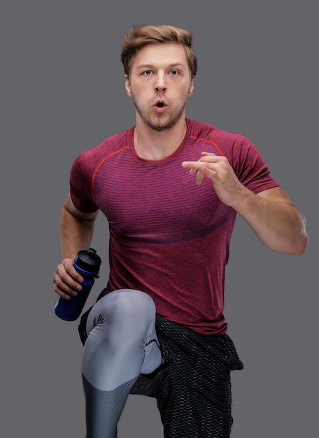 Un homme en t-shirt rouge tient une bouteille d'eau.
