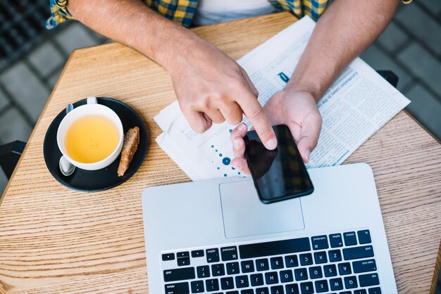 Homme à table avec du café et des gadgets