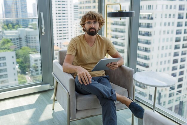 Homme avec tablette assis dans un canapé dans un bureau moderne.